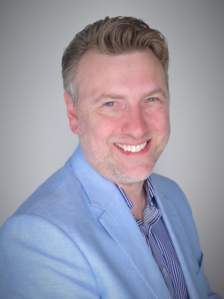Adrian Cutler Adrian Cutler smiling in a blue linen suit and blue shirt
